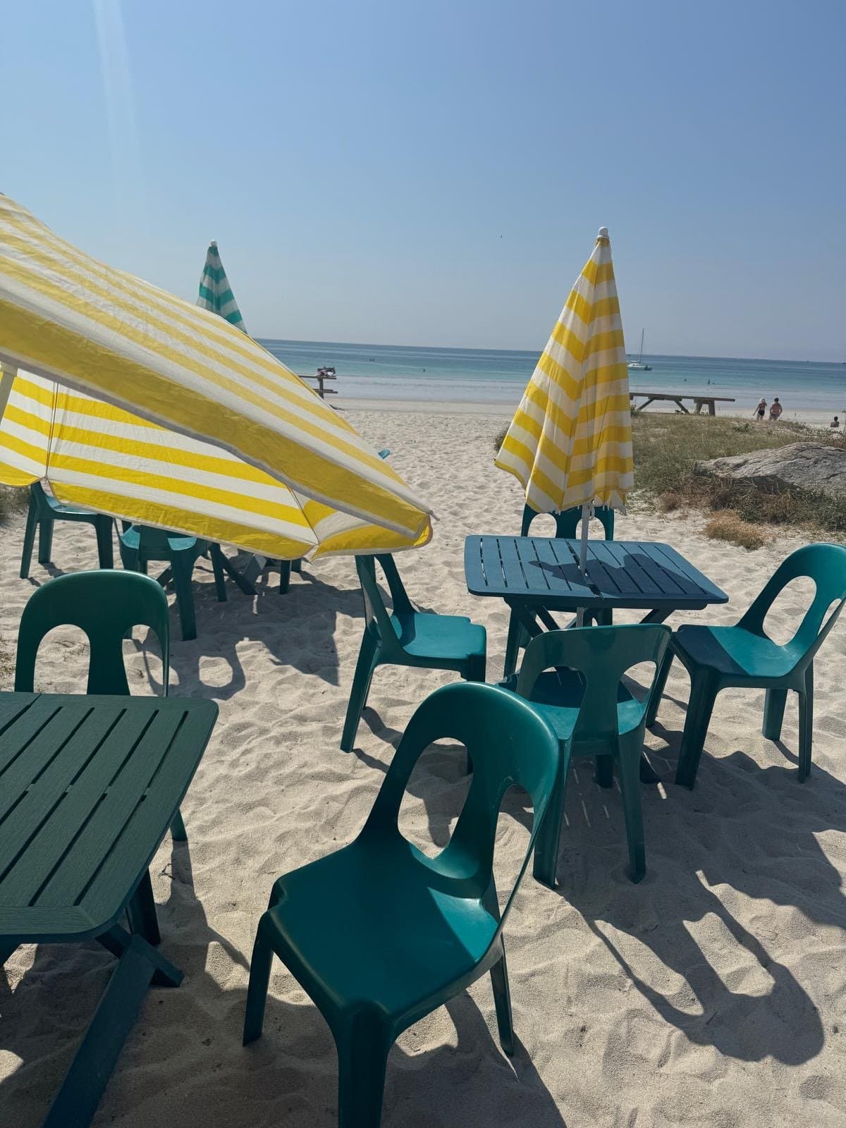 La terrasse de « Sea, sun, and… crêp’ » sur la plage du Steir : tables, parasols et sable.